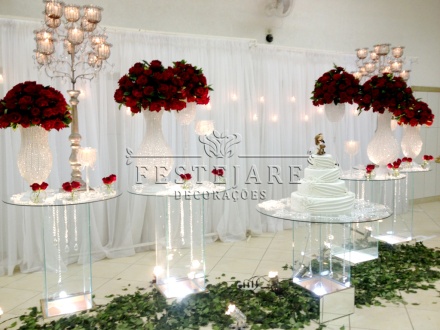 Mesa do bolo com rosas vermelhas e vasos de cristal
